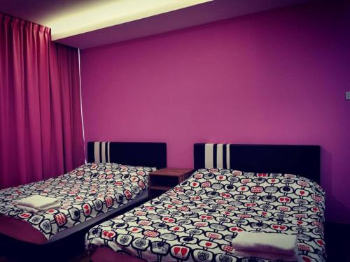 two beds in a room with purple walls at Perfect Getaway @Vivacity in Kuching
