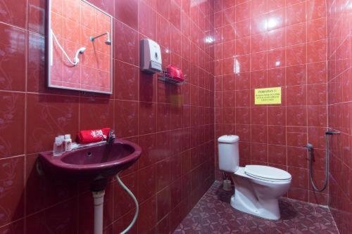 czerwona łazienka z toaletą i umywalką w obiekcie NABILA HOMESTAY w mieście Pantai Cenang