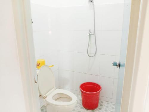 een badkamer met een toilet en een rode emmer bij OYO 3303 Penginapan Putri Asih Sawarna in Sawarna