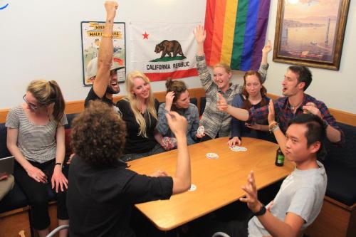 a group of people sitting around a table with their hands in the air at ITH Pacific Tradewinds Hostel in San Francisco