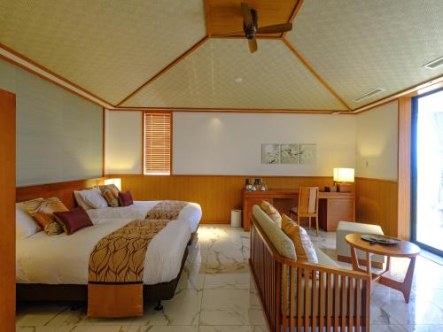 a bedroom with a large bed and a table and a couch at Miyakojima Kurima Resort Seawood Hotel in Miyako Island