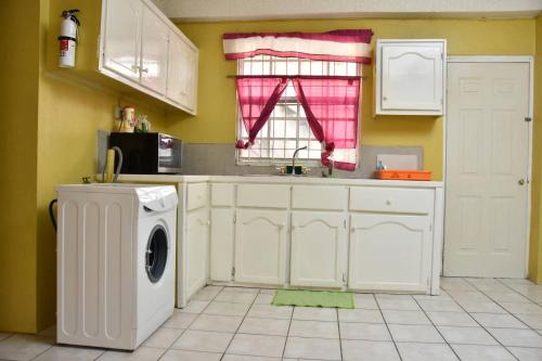 a kitchen with a washing machine and a window at Aanola Villas A4 Spacious Caribbean Casa in Charlotte