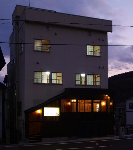 a building with a lit up facade at night at Tabataya in Myoko