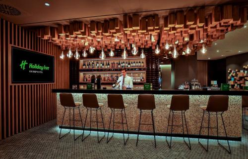 a bar in a hotel with a man behind the counter at Holiday Inn - Villingen - Schwenningen by IHG in Villingen-Schwenningen