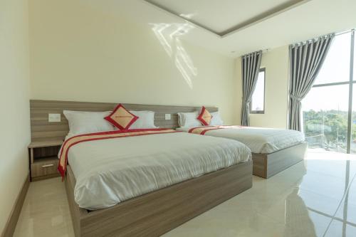 Un dormitorio con dos camas y una gran ventana. en Bamboo Hotel, en Vung Tau