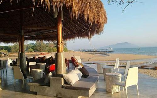 a group of chairs and a straw umbrella on a beach at The Blue Sky Resort @ Koh Payam in Ko Phayam