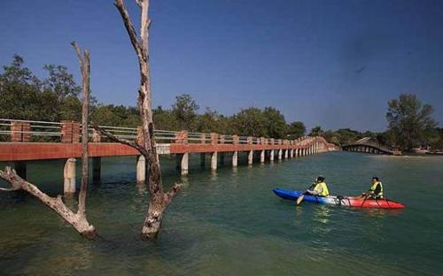 two people in a kayak in the water near a bridge at The Blue Sky Resort @ Koh Payam in Ko Phayam