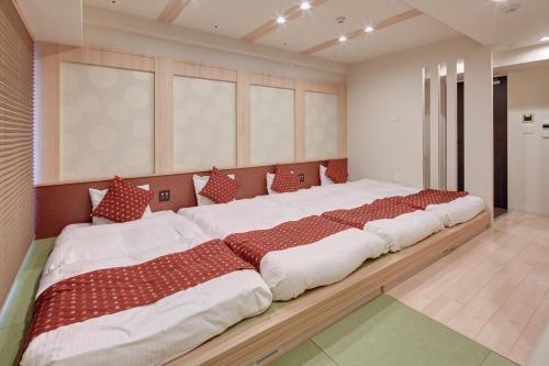 a large bedroom with two beds with red and white pillows at Hotel Amaterrace Yosuga in Osaka
