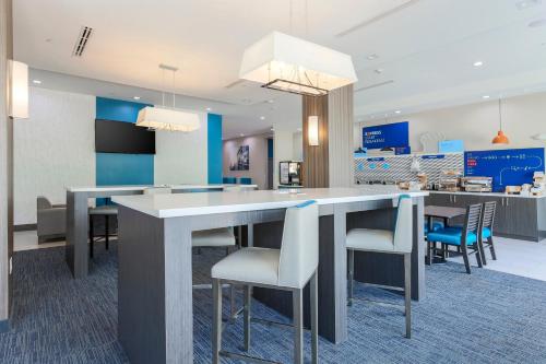 een lobby met een grote tafel en stoelen bij Holiday Inn Express & Suites Houston - Hobby Airport Area, an IHG Hotel in Houston