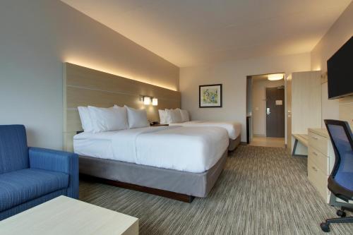 a hotel room with a large bed and a blue chair at Holiday Inn Express & Suites - Elizabethtown North by IHG in Elizabethtown