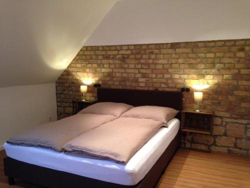 a bed in a room with a brick wall at Gästehaus Janson in Vendersheim