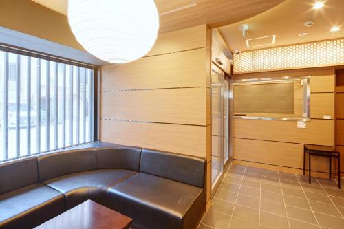a waiting room with a leather couch and a window at Hotel Amaterrace Yosuga in Osaka