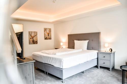 a bedroom with a large bed and a television at Parkhotel FRITZ am Brunnen in Schwelm
