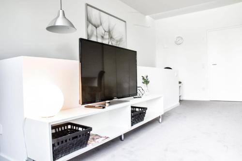 a living room with a large television on a white entertainment center at Parkhotel FRITZ am Brunnen in Schwelm