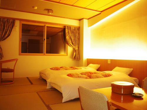 two beds in a room with two tables and chairs at Iwanai Kogen Hotel in Iwanai