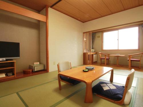 a living room with a table and chairs and a television at Iwanai Kogen Hotel in Iwanai