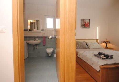 ein Schlafzimmer mit einem Bett und ein Badezimmer mit einem Waschbecken in der Unterkunft Apartment NOEL in Rogoznica