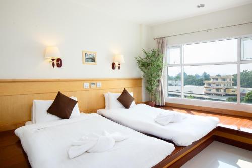 two beds in a room with a window at Kanchanaburi City Hotel - SHA Extra Plus in Kanchanaburi
