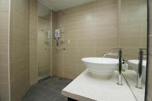 ein Badezimmer mit einem weißen Waschbecken und einer Dusche in der Unterkunft Grand Kapar Hotel Klang Sentral in Klang