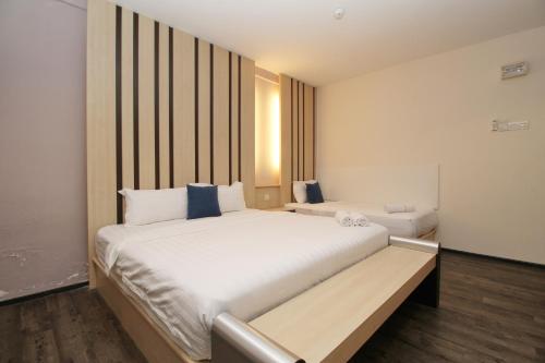 a bedroom with a large white bed with blue pillows at Grand Kapar Hotel Klang Sentral in Klang
