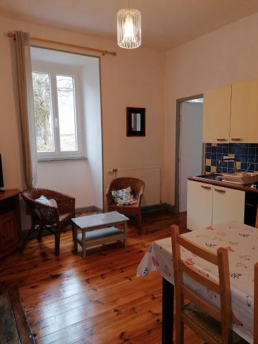 a living room with a table and chairs and a kitchen at Domaine de Salomony in Marcols-les-Eaux