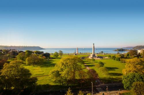 a park with a lighthouse and the ocean in the background at Crowne Plaza Plymouth by IHG in Plymouth