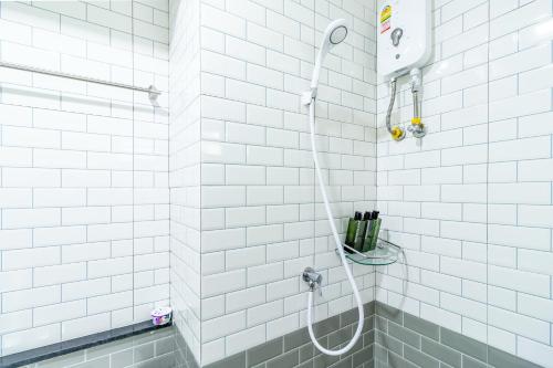 a shower with a hose in a white tiled bathroom at Be Wish Residence in Bangkok