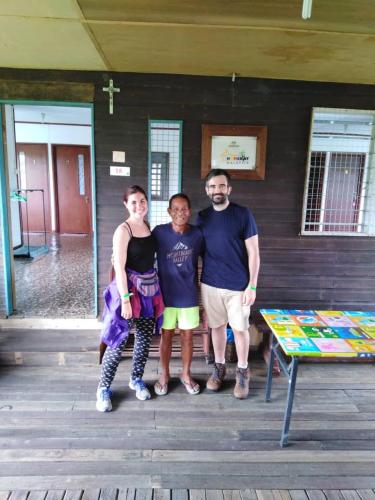 three people posing for a picture in front of a building at AA Homestay in Mulu