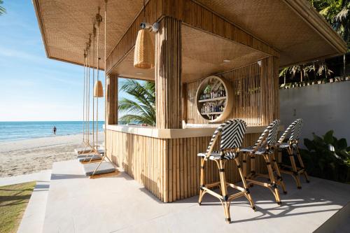 a bar on the beach with chairs and the ocean at VAYNA Boutique Koh Chang in Ko Chang
