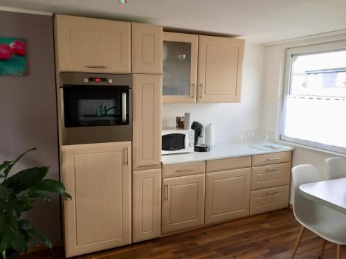 eine Küche mit weißen Schränken und einer Mikrowelle in der Unterkunft Ferienwohnung Windhaus in Dortmund