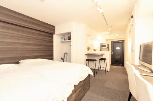 a bedroom with a large bed and a kitchen at BEEHIVE APARTMENT Moriguchi in Osaka
