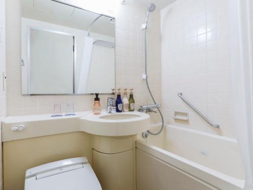a bathroom with a sink and a toilet and a mirror at ART HOTEL Aomori in Aomori