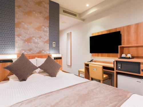 a bedroom with a bed and a desk with a television at ART HOTEL Aomori in Aomori