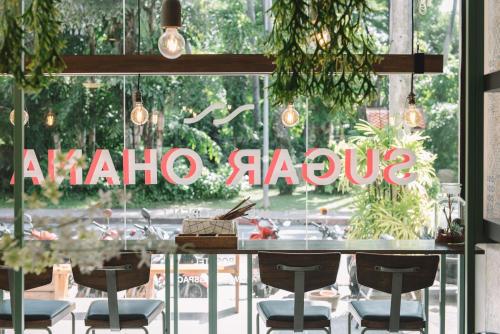 a restaurant with a table and chairs in front of a window at Sugar Ohana Poshtel in Kata Beach