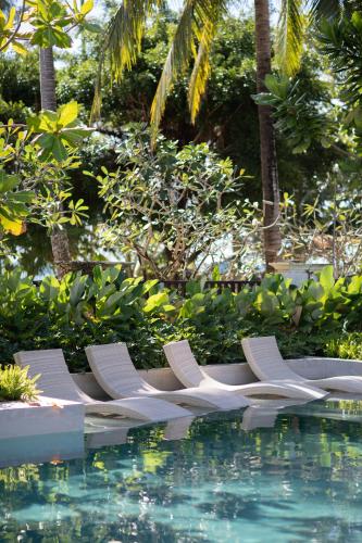 a row of lounge chairs next to a swimming pool at VAYNA Boutique Koh Chang in Ko Chang
