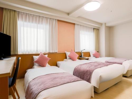 a hotel room with four beds with pink pillows at ART HOTEL Aomori in Aomori