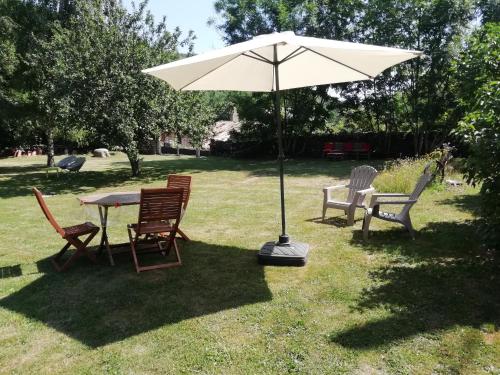 a table and chairs with an umbrella in the grass at Domaine de Salomony in Marcols-les-Eaux