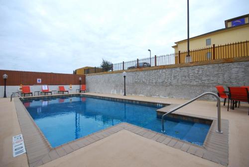 una piscina con sedie rosse e un muro di mattoni di Holiday Inn Express & Suites Gonzales, an IHG Hotel a Gonzales