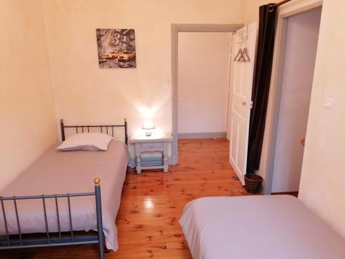 a bedroom with two beds and a table with a lamp at Domaine de Salomony in Marcols-les-Eaux