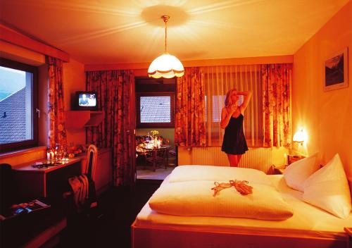 a woman standing in a bedroom with a bed at Landgasthof Jagerwirt in Volders
