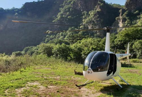 a helicopter parked in a field with a mountain at Karongwe - River Safari Lodge in Hoedspruit