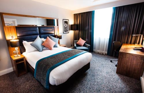 a hotel room with a large bed and a desk at Crowne Plaza Leeds by IHG in Leeds