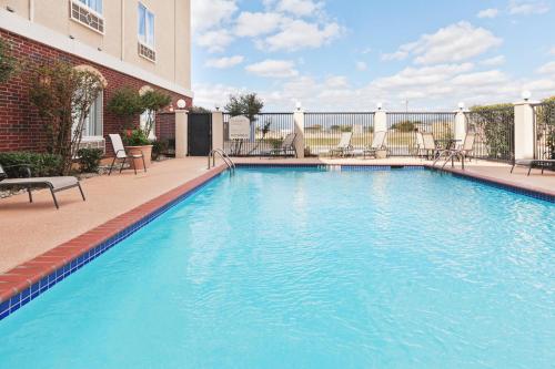 Holiday Inn Express Hotel and Suites Abilene, an IHG Hotel في أبيلين: مسبح كبير مع كراسي ومبنى