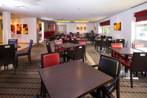 a dining room filled with tables and chairs at Holiday Inn Express East Midlands Airport by IHG in Castle Donington