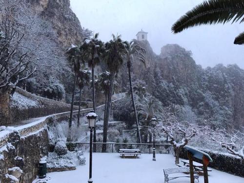 a park covered in snow with a bench and palm trees at CASA RURAL LLAVADOR Vall Guadalest in Benifató