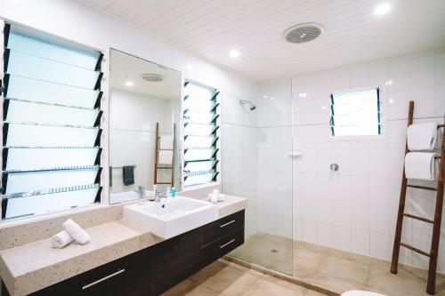 a bathroom with a sink and a shower and a mirror at Palm Bay Resort in Long Island