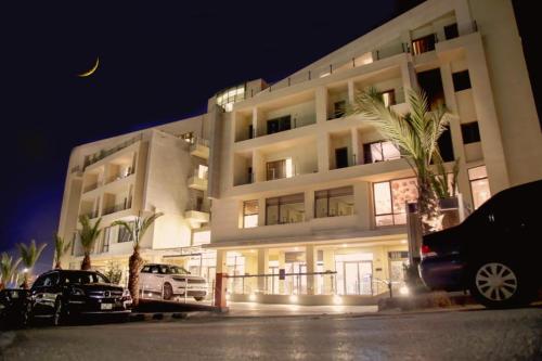 un bâtiment avec des voitures garées devant lui la nuit dans l'établissement Lijam Hotel, à Amman
