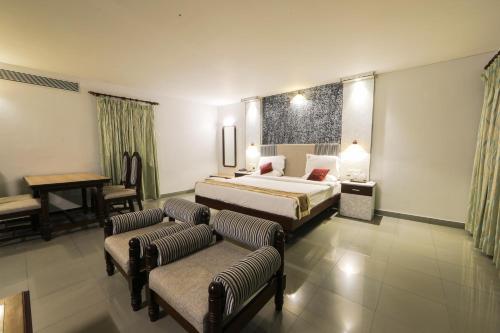 a hotel room with a bed and two chairs at Bharat Hotel in Cochin