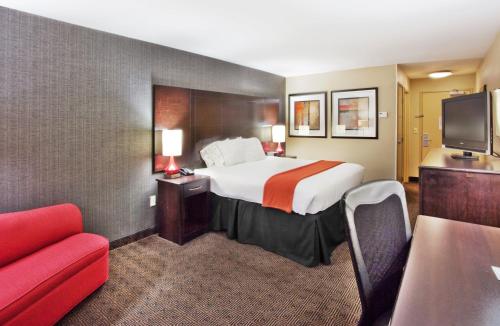 a hotel room with a bed and a red couch at Holiday Inn Express Hotel & Suites Atlanta-Cumming by IHG in Cumming