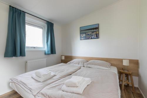 a bedroom with a large white bed with towels on it at Welcome in - Vakantiepark Fort den Haak I Nabij strand en Veerse meer in Vrouwenpolder